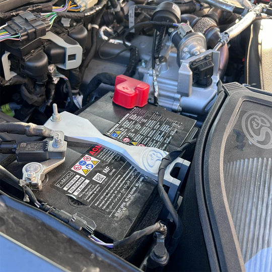 SB Filters Car billet battery hold down brackets and engine compartment with visible labels and branding.