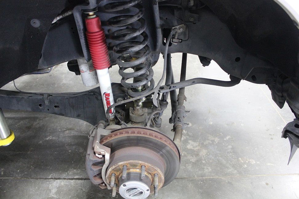 Kit of an S&B Adjustable Coil Levelers 0-2.5", 2005+ Ford Super Duty on a white background installed in a car