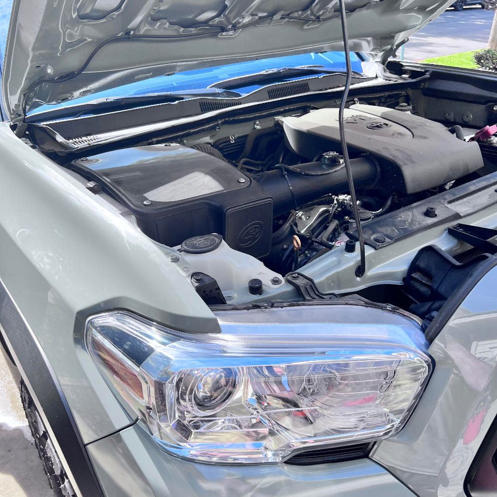 Dry Extendable Cold Air Intake for 2016-2023 Toyota Tacoma 3.5L on a white background installed in the engine compartment of a vehicle.
