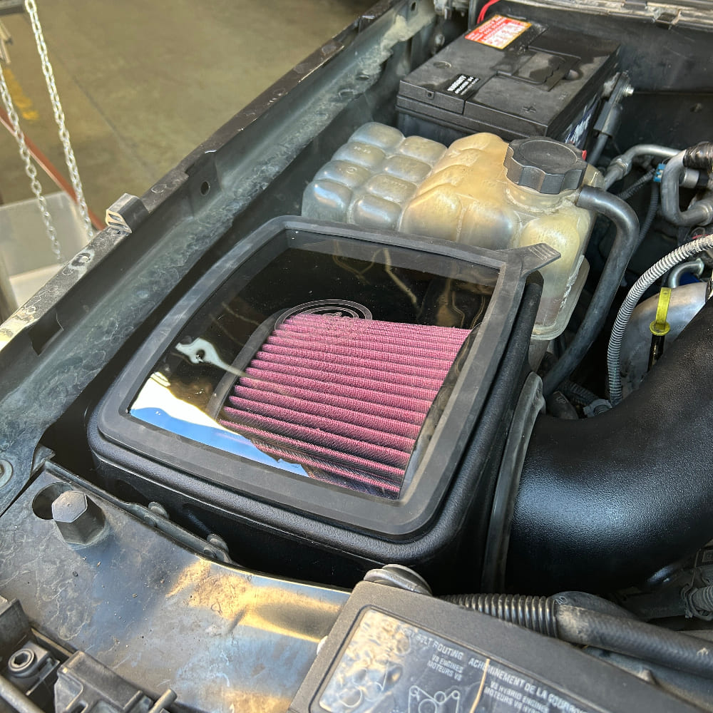 Cold Air Intake for 2004-2005 Chevy / GMC Duramax LLY 6.6L on a white background installed in the engine compartment of a vehicle.
