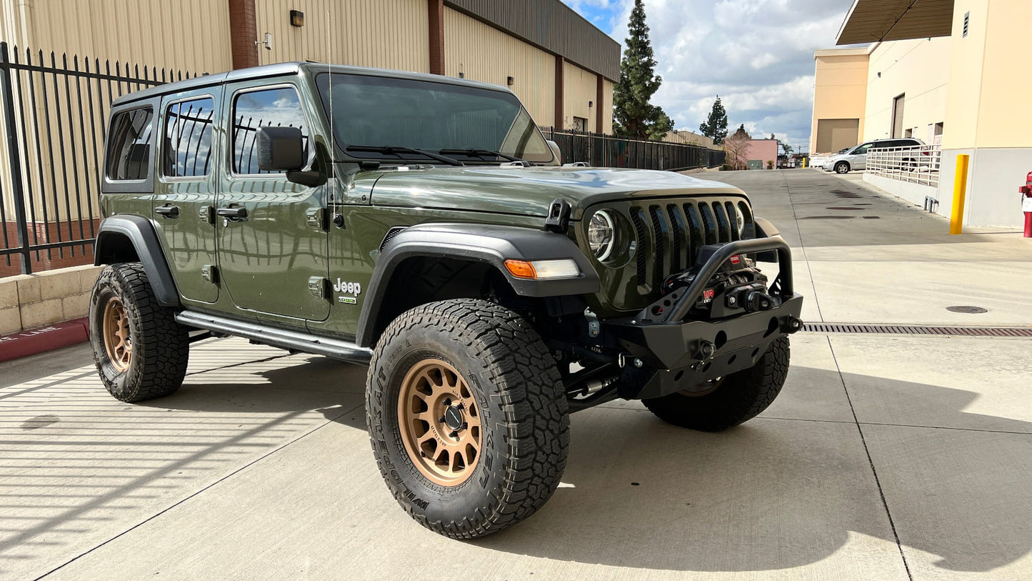 Green Jeep Wrangler parked on a concrete surface with buildings in the background