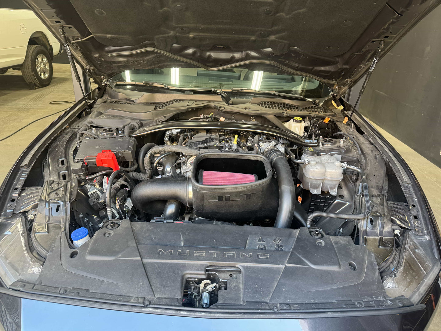 Car engine compartment with open hood, showing an SB Filters JLT Cold Air Intake For 2024-2025 Ford Mustang Ecoboost 2.3L Turbo
