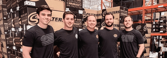 
  Five members of the SB Filters team in black t-shirts with the SB Filters logo standing in the warehouse of SB Filters.
